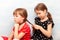 Two little school age children, sisters, siblings or close friends doing each others hair, plaiting braids together, closeup