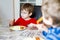 Two little school boys eating potato mash and chicken breast indoor