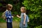 Two little school students, the boy and the girl, cheerfully communicate on the schoolyard.