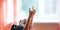 Two little schoolgirls sit at a desk in a school class and raise their hands