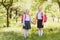 Two little Schoolgirls stand with backpacks and hold hands outdoors