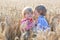 Two little sibling boys having fun and speaking on yellow wheat