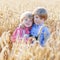 Two little sibling boys having fun and speaking on yellow wheat