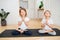 Two little siblings doing yoga at home, sitting in full lotus pose