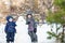 Two little siblings kids boys making a snowman, playing and having fun with snow, outdoors on cold day. Active leisure children in