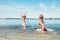 Two little sister girls fooling around in the calm sea waves splashing water to each other. Family vacation concept image