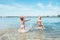 Two little sister girls fooling around in the calm sea waves splashing water to each other. Family vacation concept image