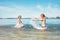 Two little sister girls fooling around in the calm sea waves splashing water to each other. Family vacation concept image