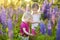 Two little sisters in blooming lupine field