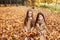 Two little sisters plays in the autumn leaves in park