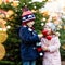 Two little smiling kids, preschool boy and girl eat sweet sugared apple on German Christmas market. Happy siblings