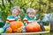 Two little twin boys making jack-o-lantern for halloween in autumn garden