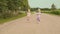 Two little twins sisters in white dresses on the road along the field. Running together. Far Forest.