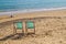 Two lonely deckchairs on a bright empty Sussex beach