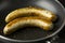 Two long bratwurst sausage grill with Italian mix herb in the hot non stick pan