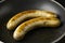Two long bratwurst sausage grill with Italian mix herb in the hot non stick pan