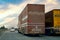 Two long covered trucks overtaking with a car in the distance on a long indian highway