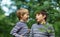 Two lovely brothers sitting in park with flowers hugging