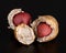 Two lovely little broken peanuts in a textured shell and with bright beautiful nuts inside on a glossy black background with refle