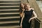 Two luxury gorgeous woman  in black dress posing, standing on old stairs in city, classic gothic lady outfit