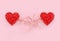 Two luxury red hearts connected by roots on pastel pink paper background. Concept Happy Valentines day. Glitter love confetti