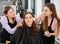 Two makeup artists applying decorative cosmetics to young female client