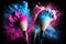 Two makeup brushes with blue and pink exploding powder on black background