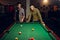 Two male billiard players with cue, poolroom