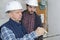 Two male contractors holding clipboard by electric meter