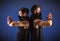 Two male dancers posing in ninja costumes against blue background.