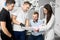 Two male dentists and their female assistant are showing the paper to a satisfied male client of the dental office