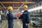 Two male engineers in protective hardhats and workwear greeting one another by handshake