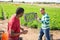 Two male farm worker fighting on field