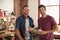 Two male friends hanging out in kitchen looking to camera