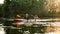 Two male friends looking cheerful while boating together on a lake surrounded by peaceful nature