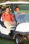 Two Male Golfers Riding In Golf Buggy