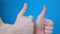 Two male hands showing thumbs up on bright blue background. They show class.