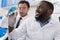 Two Male Laboratory Scientists Examining Samples Injection In Syringe, Mix Race Doctors In Lab Study Results Of Chemical