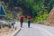 Two male longboarders carrying their longboards in their hands while climbing uphill and preparing for a downhill slide. Wearing