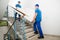 Two Male Movers Carrying Sofa On Staircase