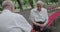 Two male pensioners spend leisure time on a street bench, talk and play chess