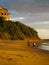 Two male surfers walk on wide beach carrying surfboards in Nicaragua at low tide