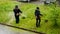 Two male utility workers mow grass