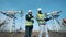 Two male workers are talking in front of functioning oil-derricks. Energy, oil, gas, fuel pumping rig.