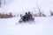 Two man on a snowmobile riding on the snow surface in the winter forest