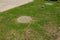Two manhole covers on the green lawn of a septic tank system, sewer with a vent pipe installed in the ground. A septic tank in the