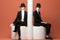 Two mannequins dressed in suits and hats sitting on pedestals. Generative AI image.