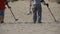 Two Mans with a Metal Detector Walks along a Sandy Beach on the Seashore. Slow Motion