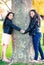 Two Maori sisters holding hands hugging a tree