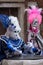 Two masked women in costume with fans and ornate painted feathered masks at Venice Carnival.